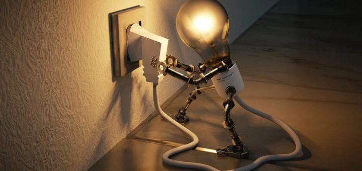 Eine Figur in Form einer Glühbirne steckt den mit dem eigenen Körper verbundenen Stecker in eine Steckdose und leuchtet