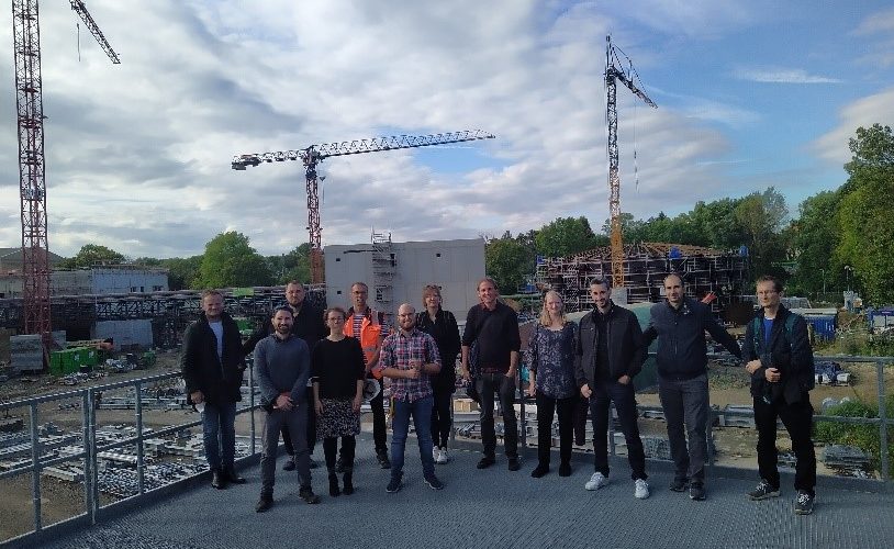 Das Foto zeigt eine 12-köpfige Gruppe Menschen (Besuch aus Kladno und Prag)vor der Kulisse einer Baustelle