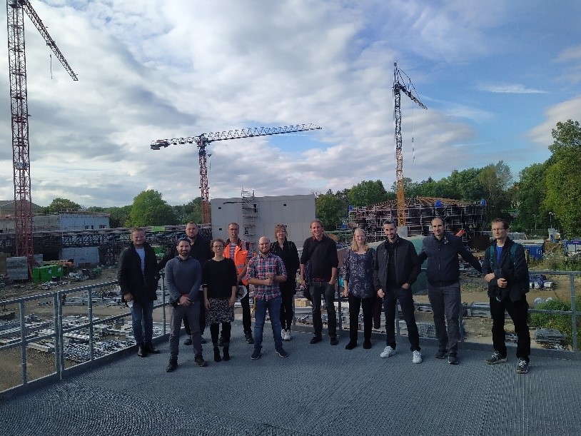 Das Foto zeigt eine 12-köpfige Gruppe Menschen (Besuch aus Kladno und Prag)vor der Kulisse einer Baustelle