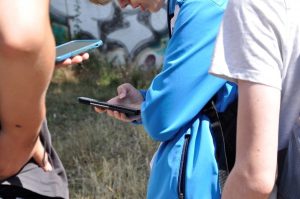 Auf dem Bild sieht man drei Schüler der digitalen Exkursion mit ihren Smartphones
