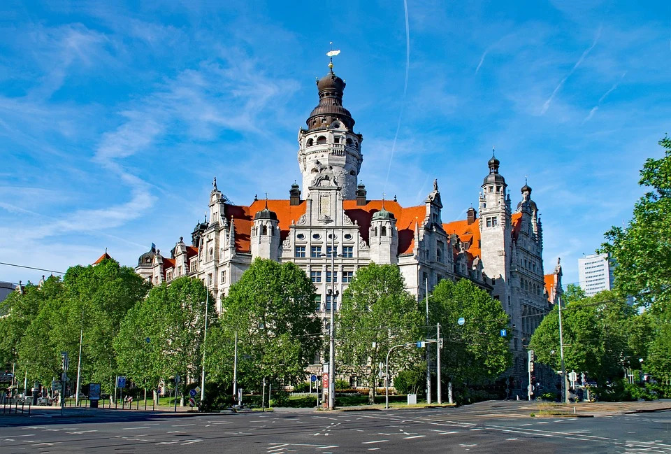 Das neue Rathaus Leipzigs, umgeben von grünen Bäumen bei blauem Himmel