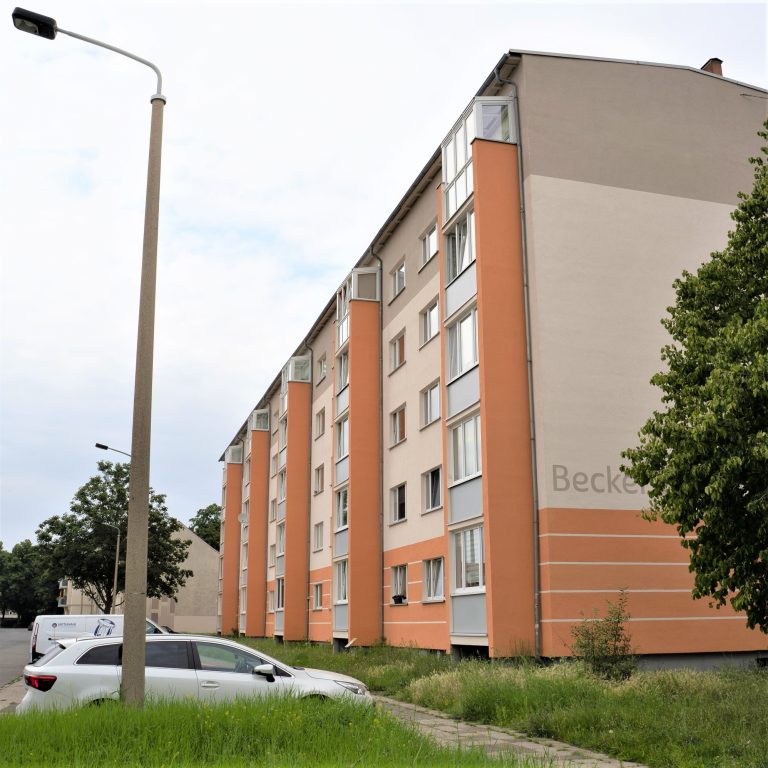 Das Foto zeigt orange-beige Häuser im Dunckerviertel, einen Baum sowie ein parkendes Auto vorne im Bild.