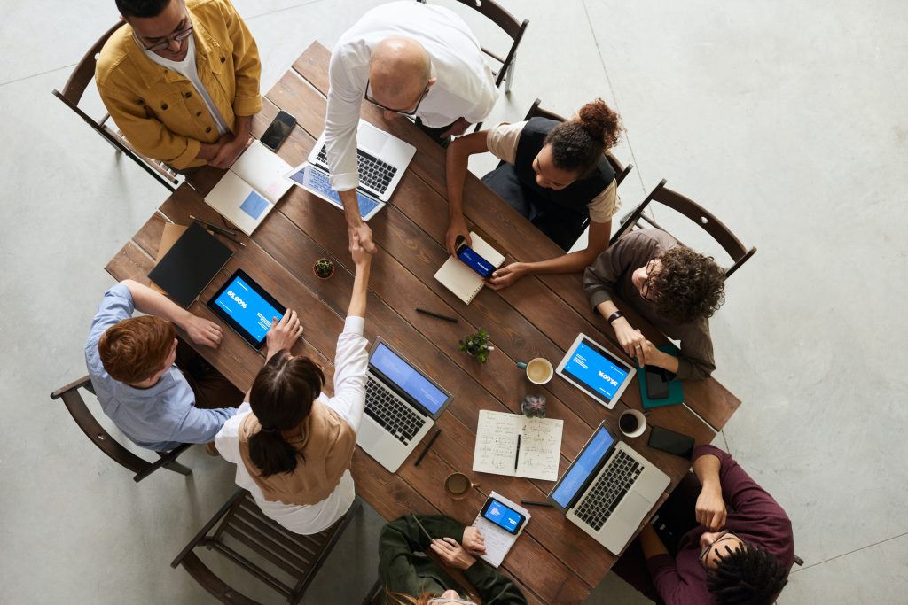 Auf dem Bild sieht man eine Runde von Personen an einem Tisch die miteinander arbeiten und diskutieren